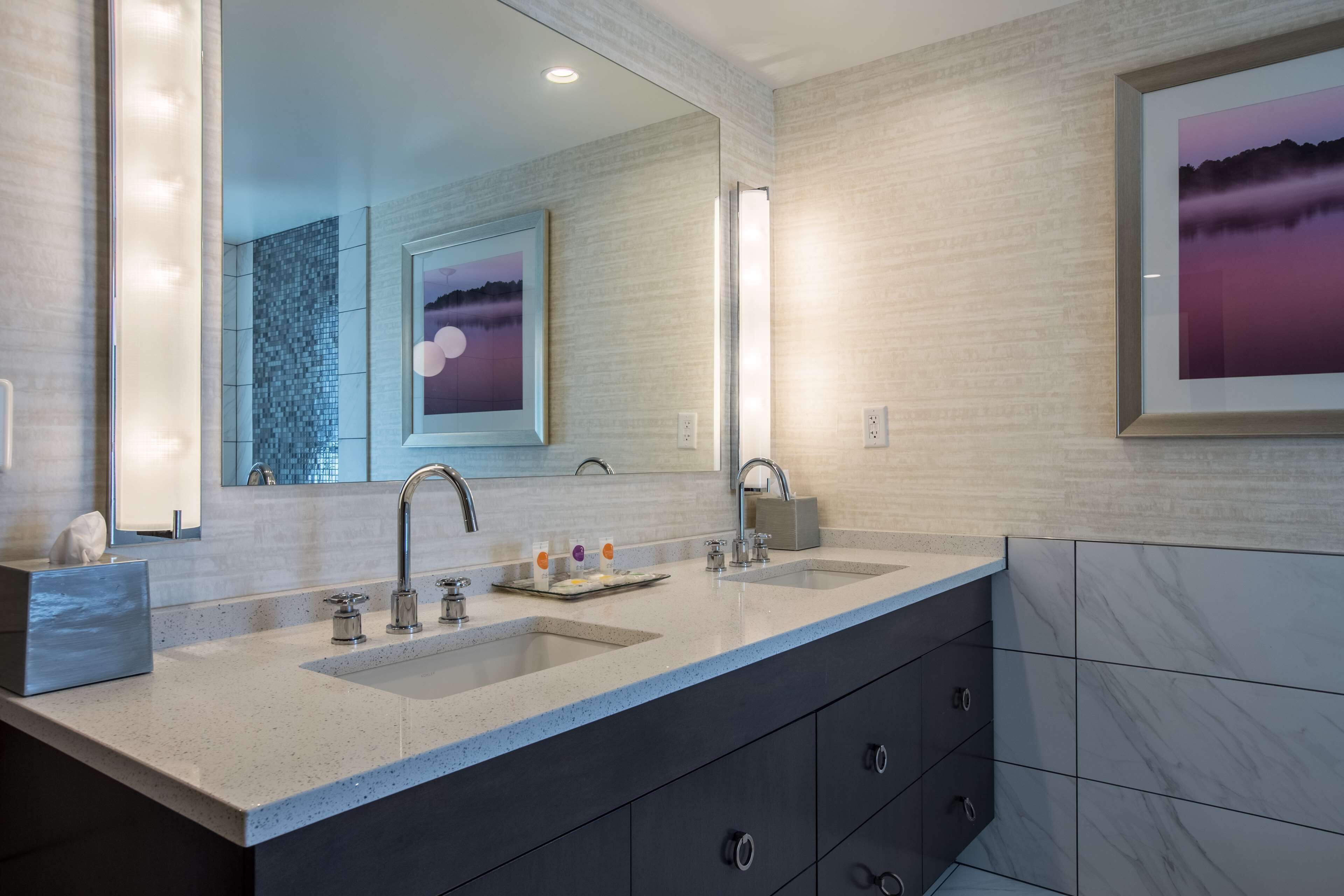 A modern bathroom with a large mirror, two sinks, and a dark cabinet.