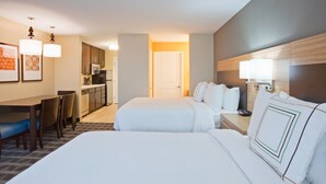 Una habitación de hotel con una cama grande, un escritorio, una silla y una kitchenette.