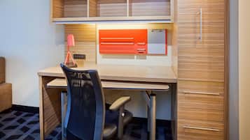 Un espacio de oficina moderno con un escritorio de madera, una silla, una estantería con compartimentos y un armario con cajones.