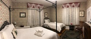 A four-poster bed with white linens, two bedside tables, and a small round table with a chair. - The Colonel's Inn (Prescott)