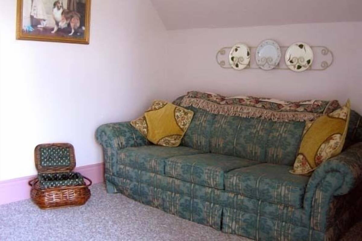 A room with a green patterned sofa, a wicker basket, and a framed picture on the wall.