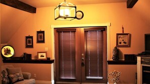 Una sala de estar con sofá, una mesa de centro, chimenea y una puerta con persianas.