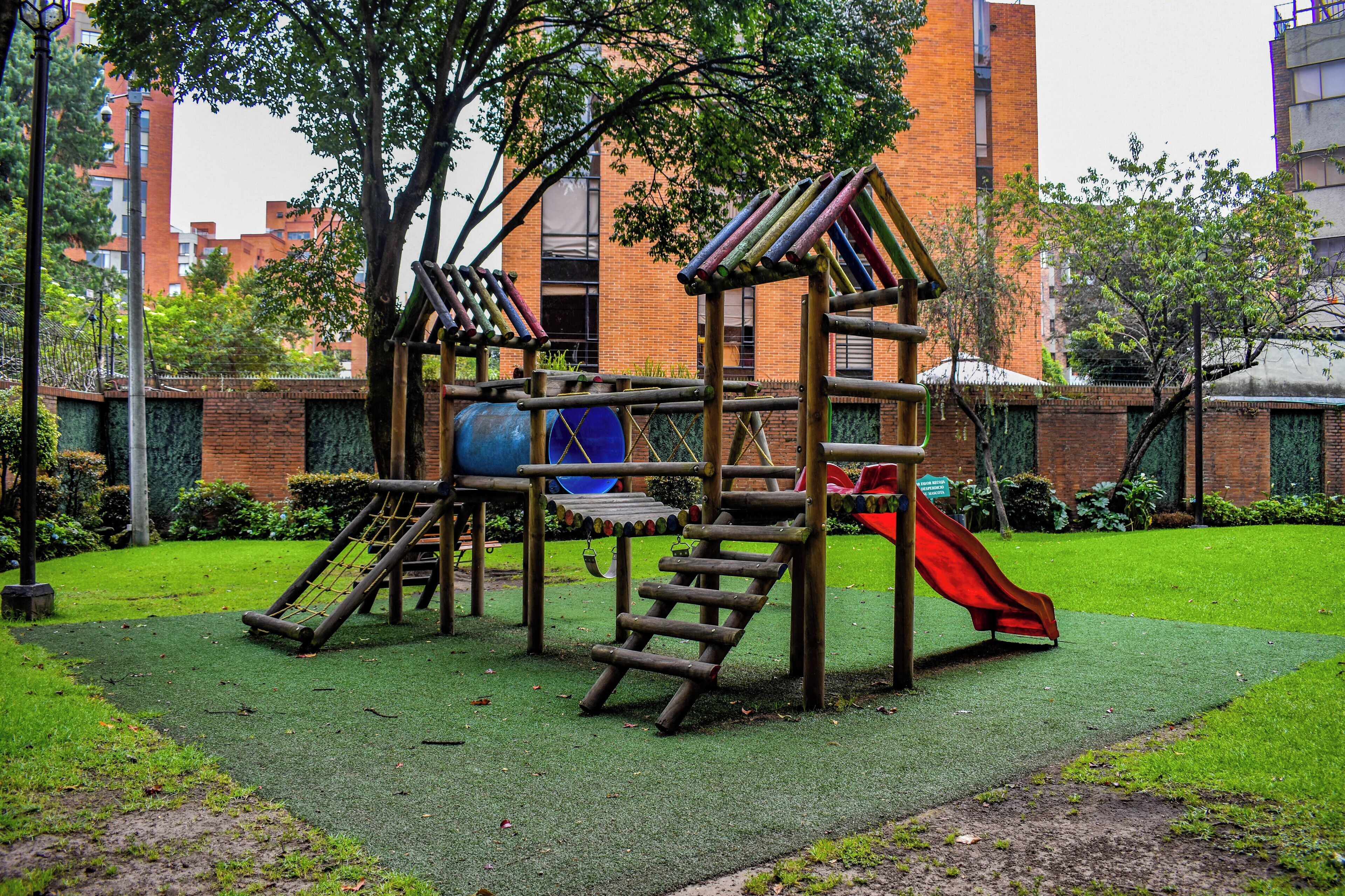 A playground with a slide, climbing net, and a blue ball.