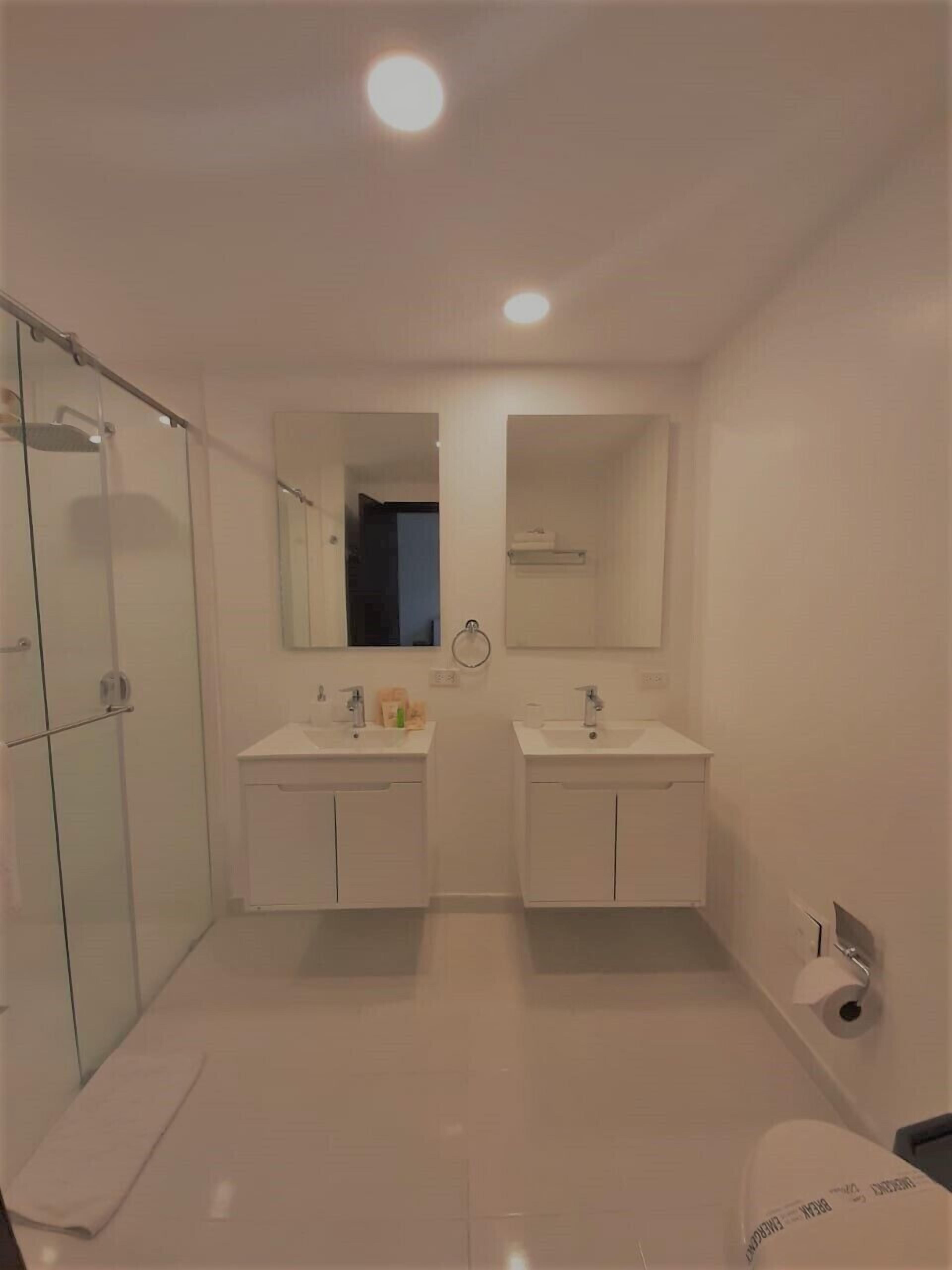 A modern bathroom with two sinks, a glass shower enclosure, and a mirror above the sinks.
