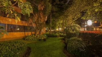 Un jardín cuidado con un sendero que lleva a un edificio de grandes ventanales y fachada de ladrillo.
