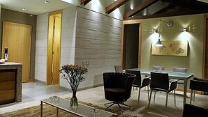 Un interior moderno con zona de comedor, una mesa de centro de cristal y un jarrón con flores.
