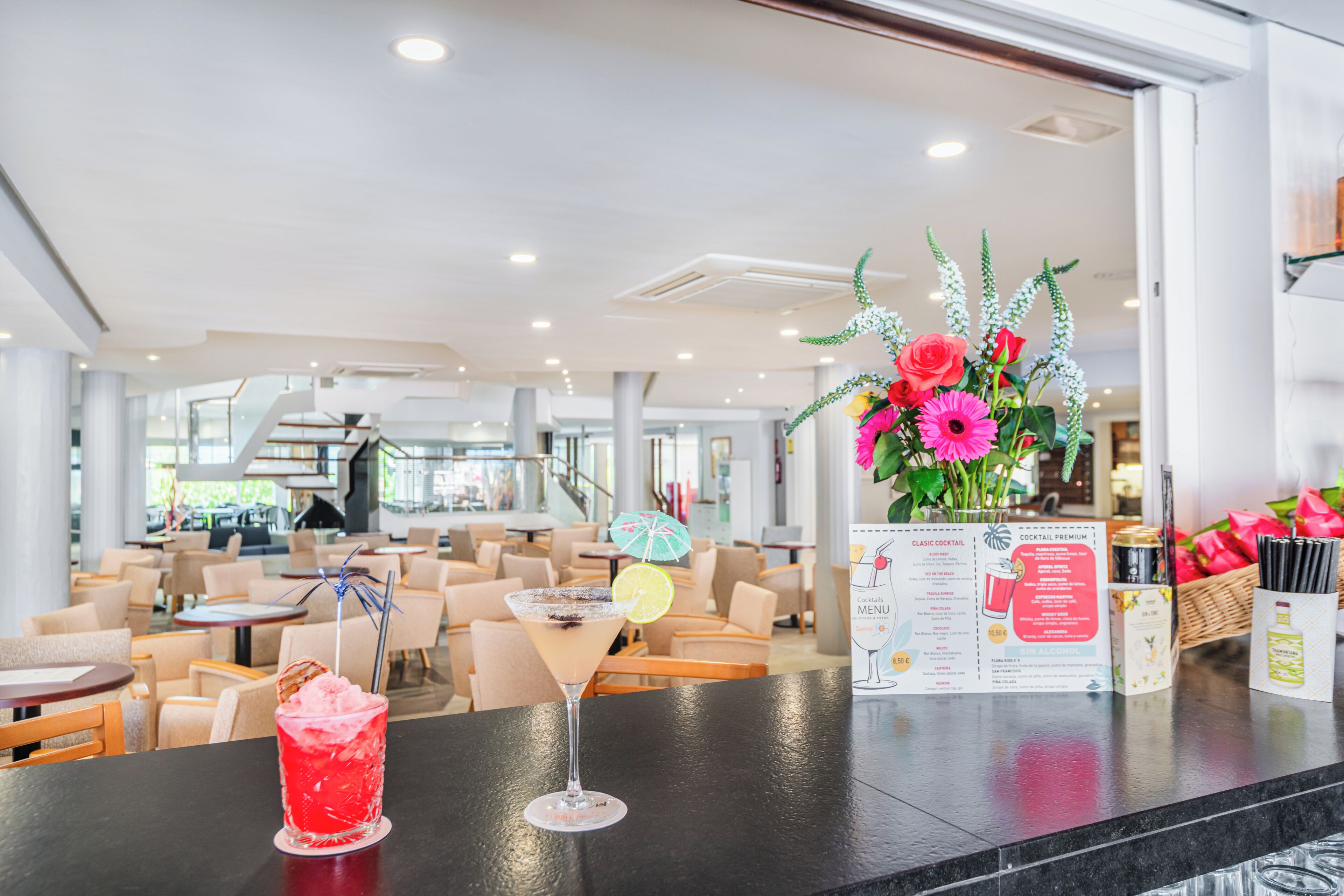 A bar area with a cocktail, a menu, and a flower arrangement.