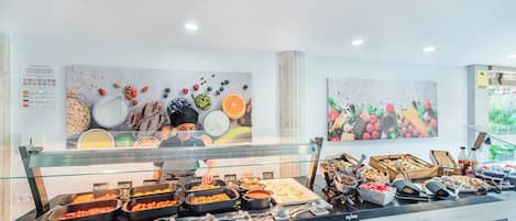 Un buffet proposant une variété de plats, notamment des viandes, des fruits et des desserts.