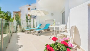 A balcony with a table, chairs, and a sun umbrella.