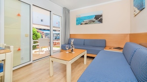 A modern room with a sofa, a table with glasses, and a view of the sea through a glass door.