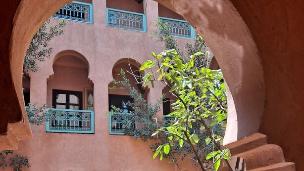 A courtyard with arches, potted plants, and a fountain. - Kasbah Omar (Ourika)