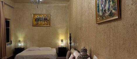 Une chambre d’hôtel avec deux lits, un lustre, un tableau et une table de chevet avec une lampe.