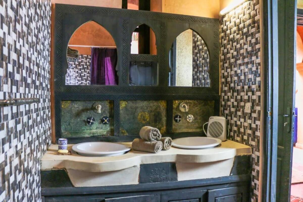 A bathroom with a large mirror, two sinks, and a towel rack.