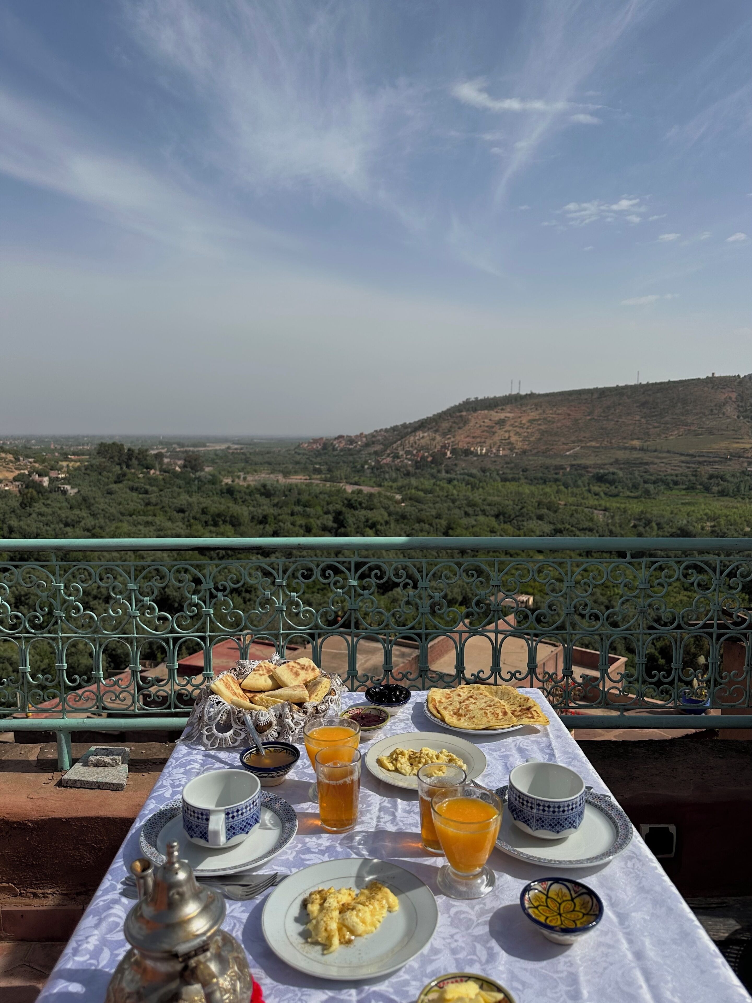 A table set with breakfast items and a view of a hilly landscape.