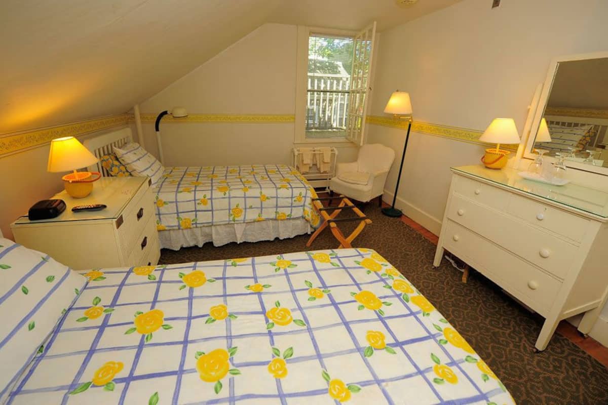 Un dormitorio con dos camas, una silla, un aparador y una ventana con vistas.