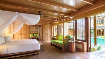 A spacious bedroom with a large bed, a green sofa, and a view of a swimming pool.