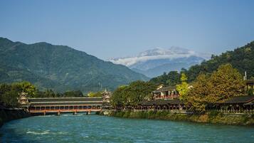A riverside view with a traditional building and a bridge.