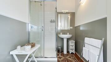 A modern bathroom with a glass shower enclosure, a white sink, and a vanity with a mirror.