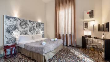 A hotel room with a bed, a desk, a chair, a TV, and a curtain.