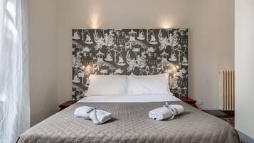 A neatly made bed with a quilted bedspread and two towels placed on the bed.
