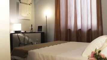 A hotel room with a bed, a desk, a chair, a lamp, and a wall with a calendar.