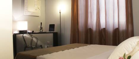 Habitación de hotel con cama, escritorio, silla, lámpara y una pared con un calendario.
