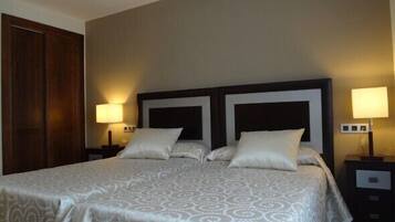 Una habitación de hotel con una cama grande, dos mesitas de noche y un armario de madera.