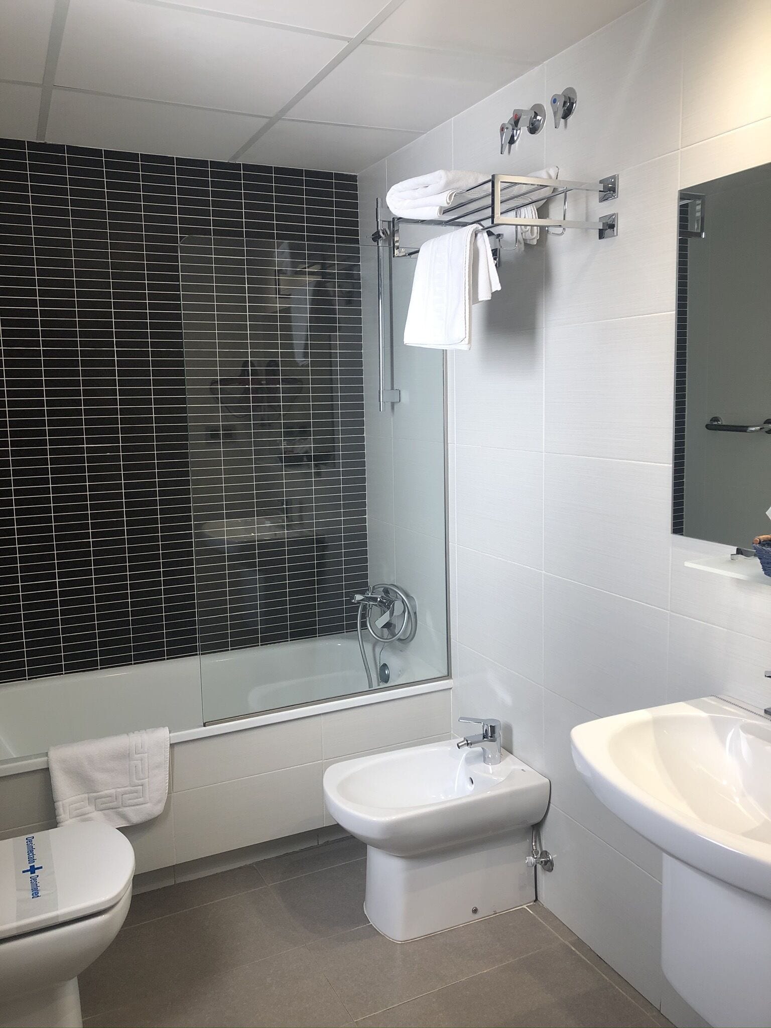 A modern bathroom with a glass shower enclosure, a bidet, a toilet, and a sink.