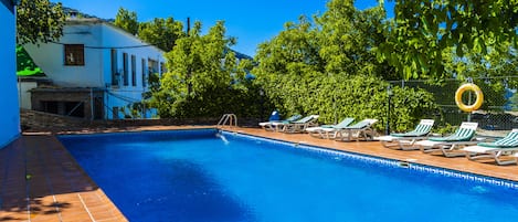 Een seizoensgebonden buitenzwembad en ligstoelen