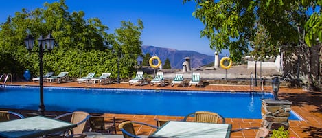 Una piscina al aire libre de temporada, sillones reclinables de piscina