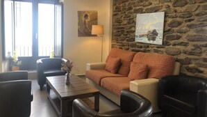 Un salón con pared de piedra, un sofá, una mesa de centro y una lámpara.