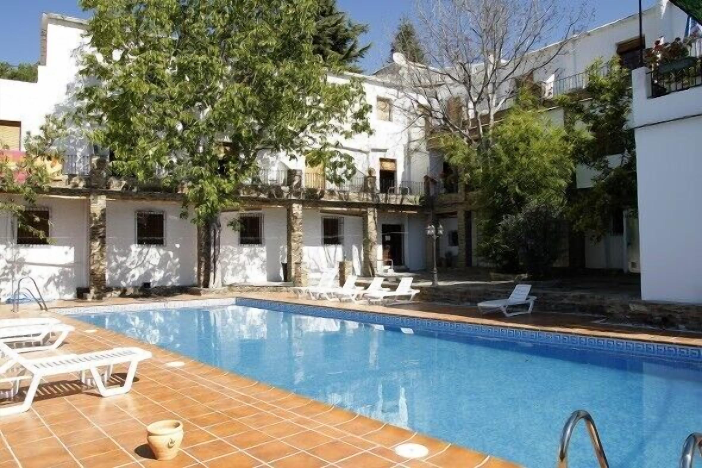 A swimming pool with lounge chairs and a tiled deck.