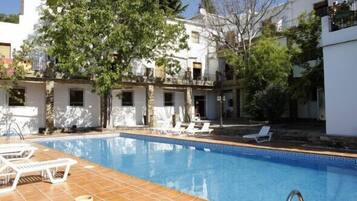 A swimming pool with lounge chairs and a tiled deck.