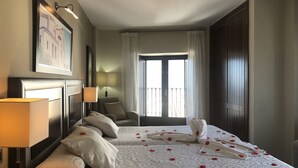 Habitación de hotel con una cama grande, una silla, un escritorio, una lámpara y una ventana con cortinas.
