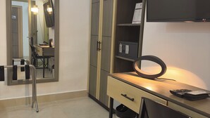 A modern hotel room with a desk, a mirror, a wardrobe, and a television. - Hotel Merlott Lleras (Medellín)