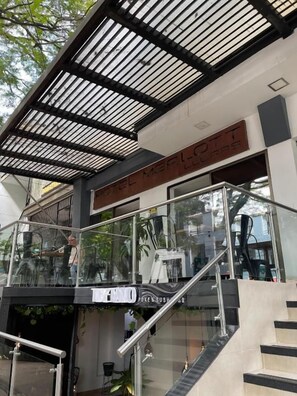 A hotel entrance with a glass facade, a staircase, and a sign indicating a restaurant. - Hotel Merlott Lleras (Medellín)