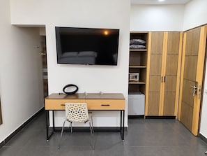 A compact room with a desk, chair, TV, wardrobe, and a microwave. - Hotel Merlott Lleras (Medellín)
