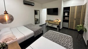 A modern hotel room with two beds, a desk, a TV, a wardrobe, and a hanging light fixture. - Hotel Merlott Lleras (Medellín)