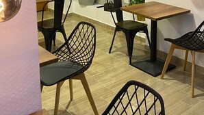 Un comedor con mesa y sillas de madera, una planta en maceta y un televisor montado en la pared.