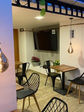 Un comedor con mesa y sillas de madera, una planta en maceta y un televisor montado en la pared.