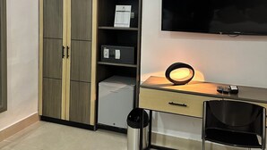 A bedroom with a wardrobe, a desk, a chair, a TV, and a trash bin. - Hotel Merlott Lleras (Medellín)