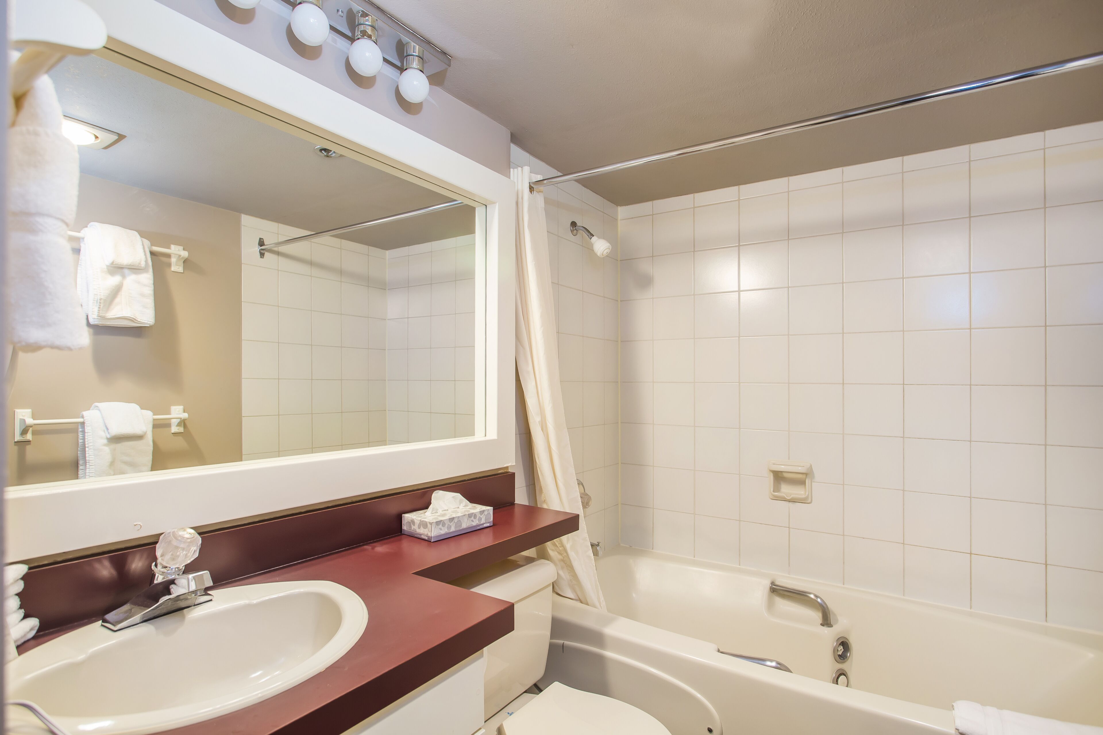 Een badkamer met een wastafel, spiegel en bad.