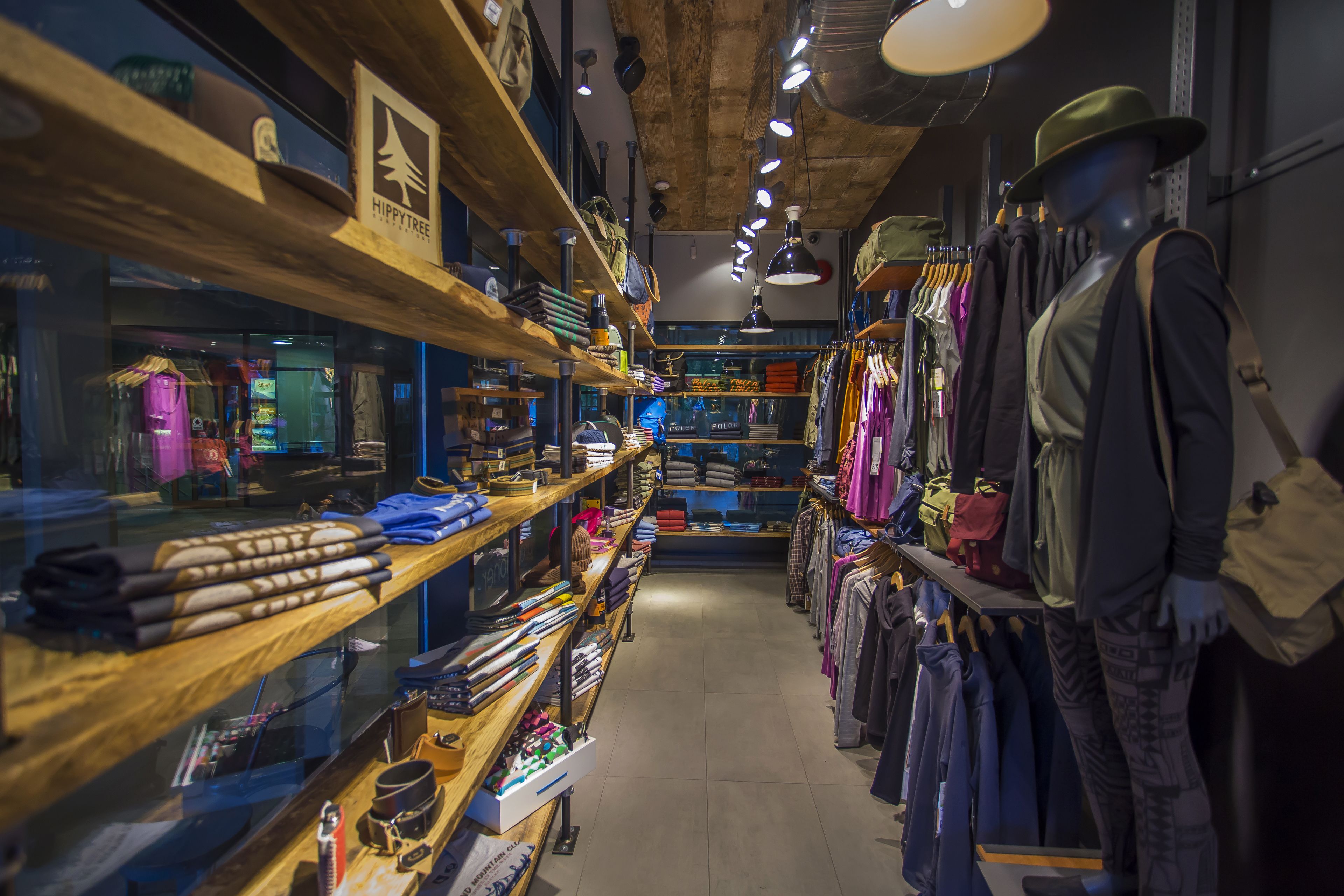 A clothing store with wooden shelves and racks displaying various garments and accessories.