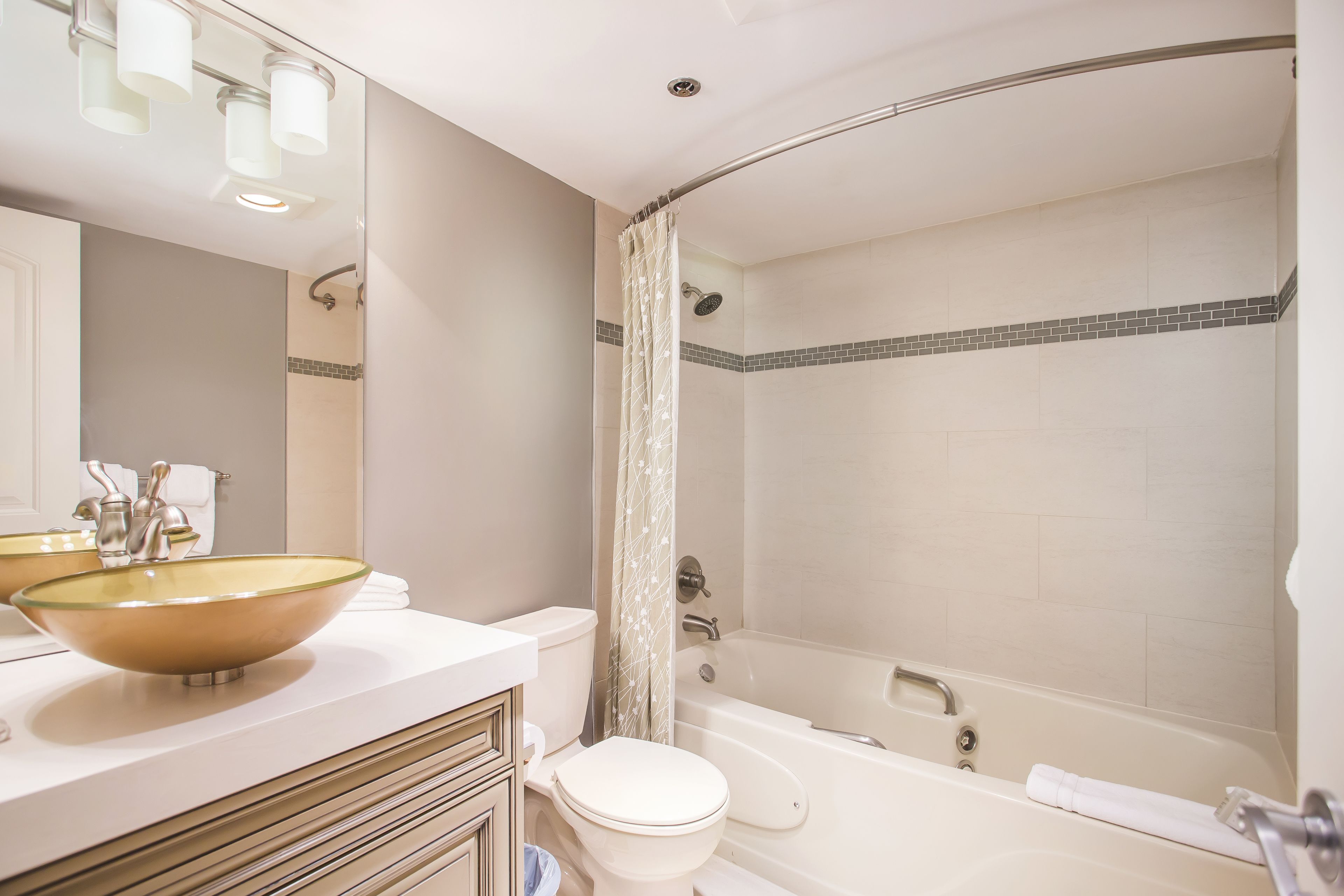 Ein Badezimmer mit einem großen Waschbecken aus Glas, einer weißen Toilette, einer Badewanne und einer Duschvorhang.
