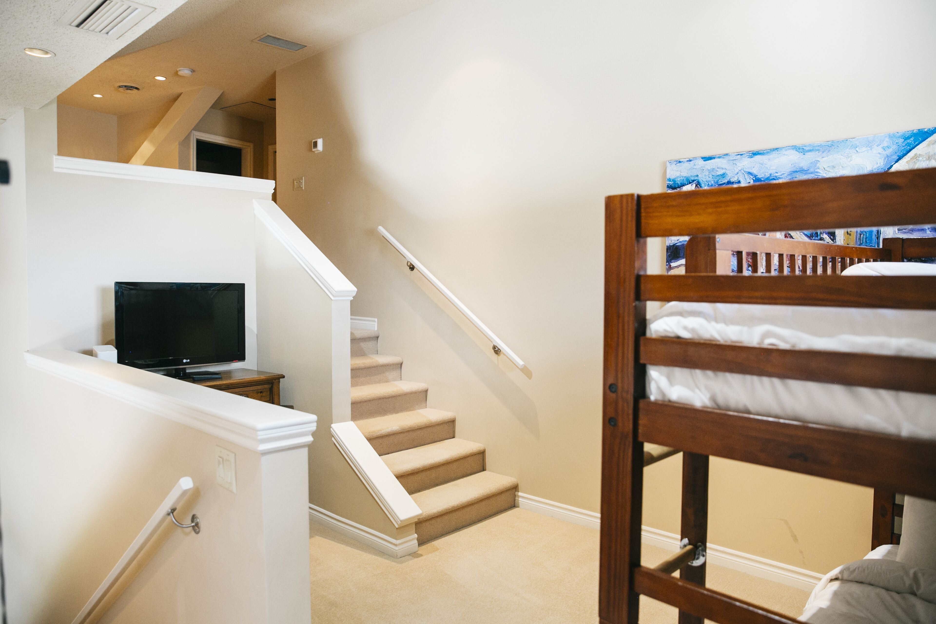 Ein Schlafzimmer mit Etagenbett, Fernseher auf einem Schrank und einer Treppe zu einer oberen Ebene.