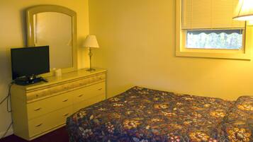 A bedroom with a bed, a dresser, a TV, a mirror, and a window with blinds.