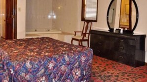 A bedroom with a bed, a chair, a dresser, a mirror, and a window with blinds. - Countryside Motel (Cold Spring)