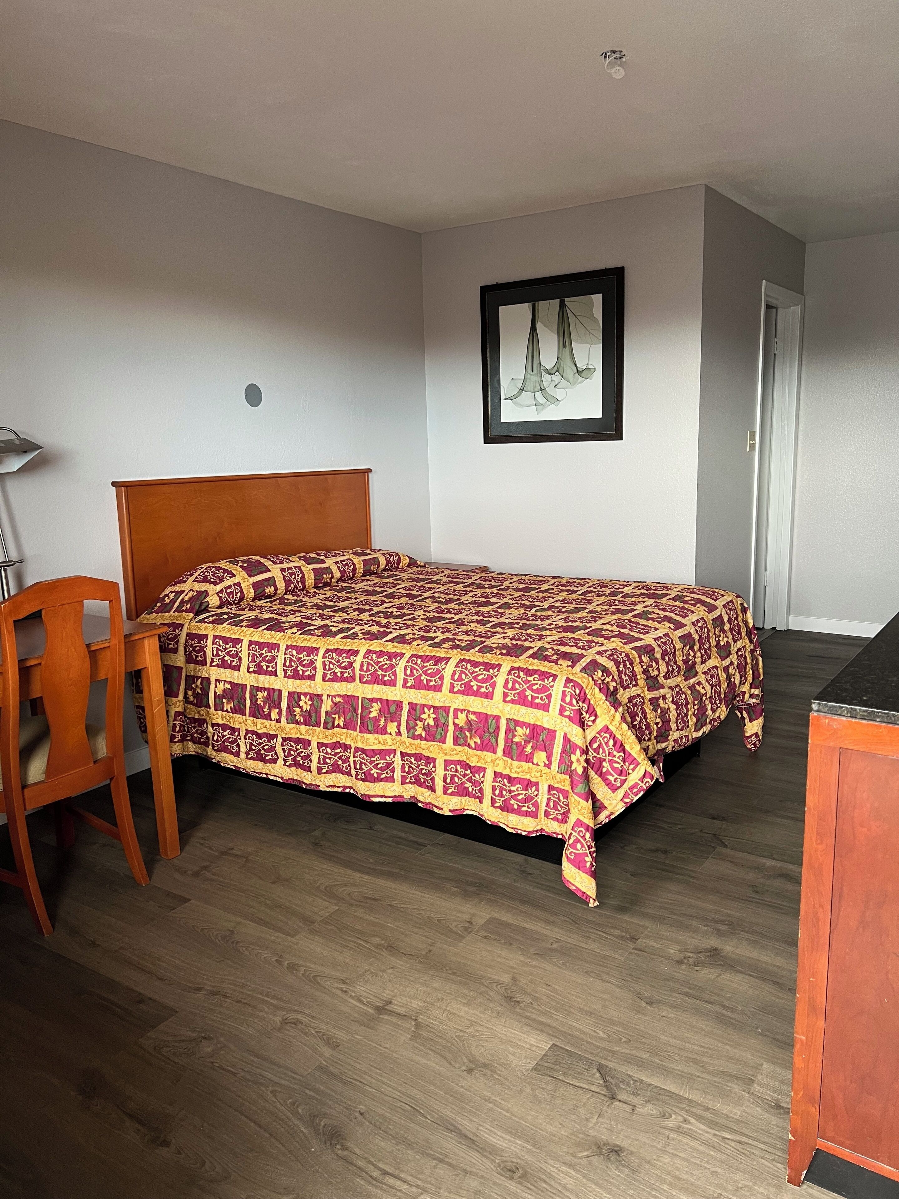 Un dormitorio con una cama de madera, un escritorio y una silla.