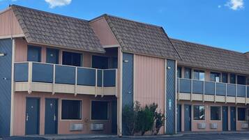 A two-story motel with a flat roof, large windows, and a covered balcony.
