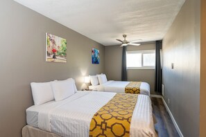 A hotel room with two beds, a ceiling fan, and artwork on the walls. - Hinton Highway Inn (Hinton)